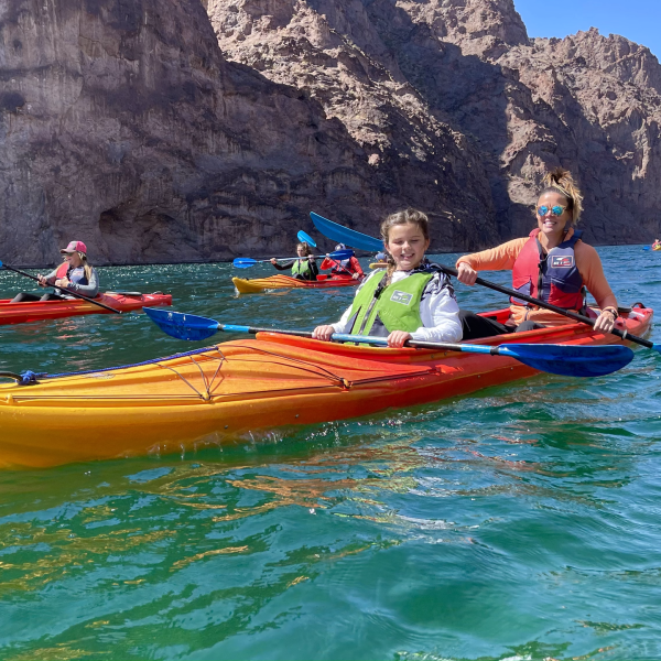 People kayaking through a rocky canyon on a sunny day.