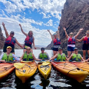 Group of people in kayaks posing happily between canyon walls.