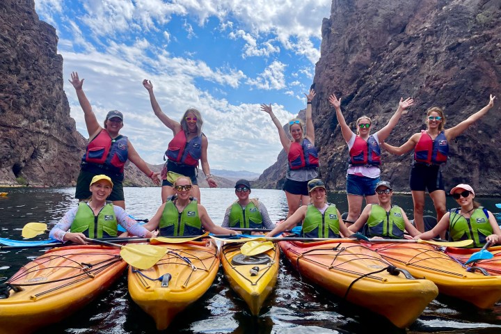 Group of people in kayaks posing happily between canyon walls.