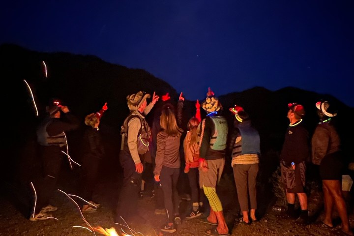 Group around campfire under night sky with visible moon.