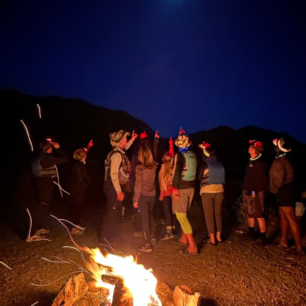 People around a campfire at night under a bright moon.