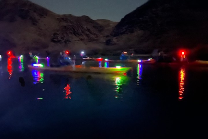 Kayaks with colorful lights on a calm water surface at night.