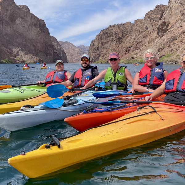 Group kayaking in canyon lake, wearing life vests.