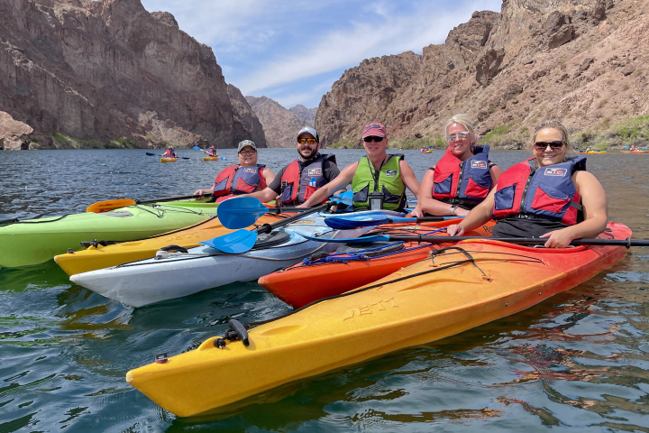 Group kayaking in canyon lake, wearing life vests.