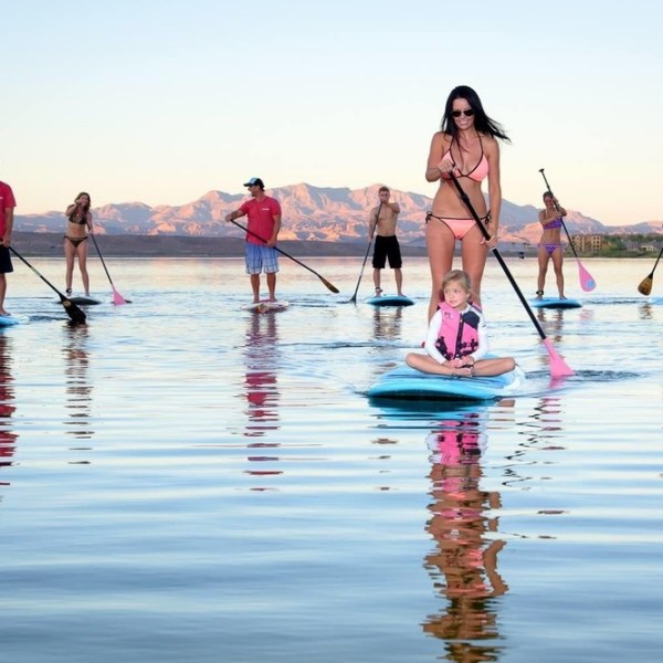 Group paddleboarding on a calm lake with mountains in the background.